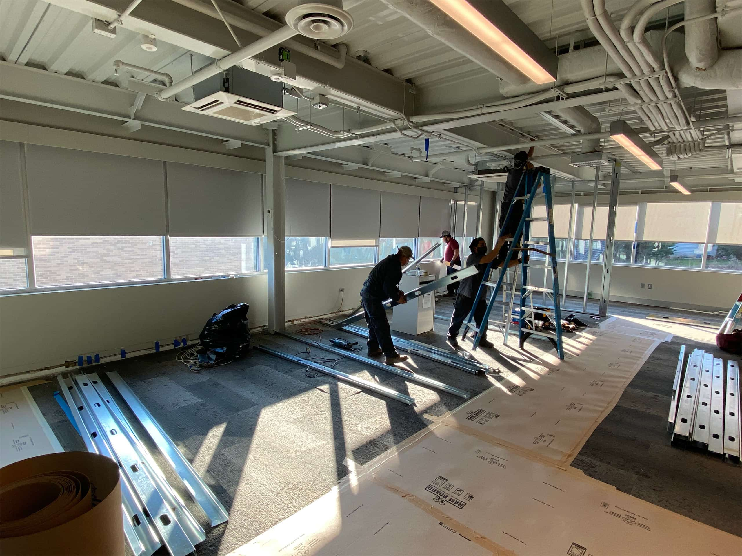 Workers building an interior wall with aluminum studs