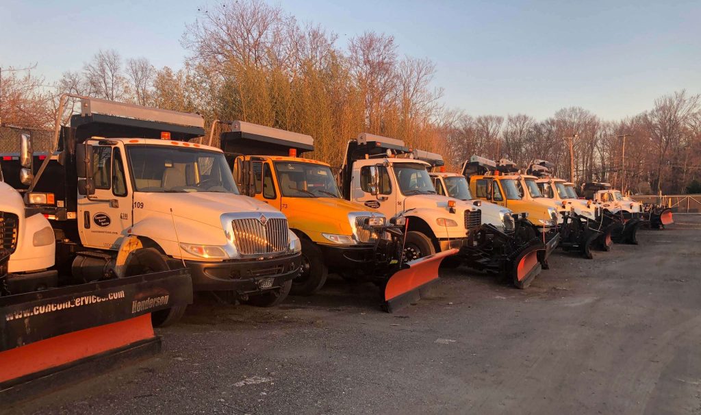 A row of trucks equipped with snow removal equipment