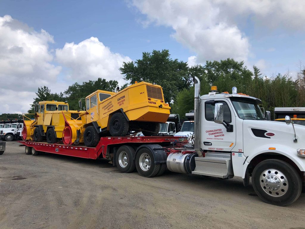 A large flat-bed truck transporting heavy construction equipment