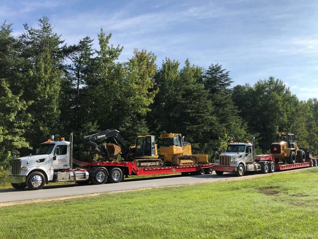 Flat-bed trucks transporting heavy construction equipment