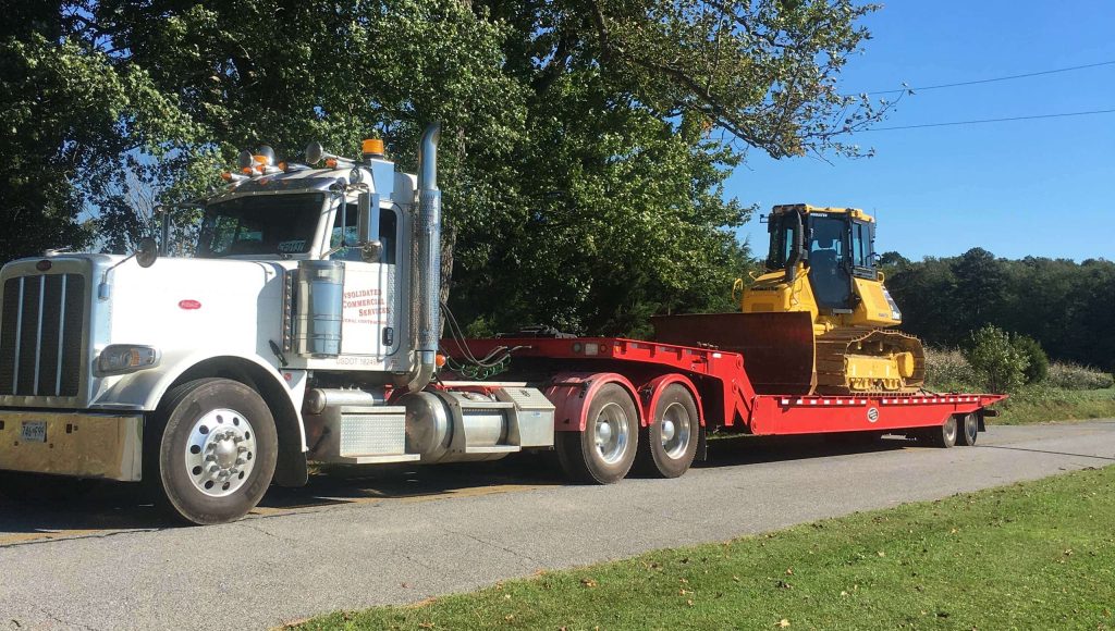 A large flat-bed truck transporting a bulldozer